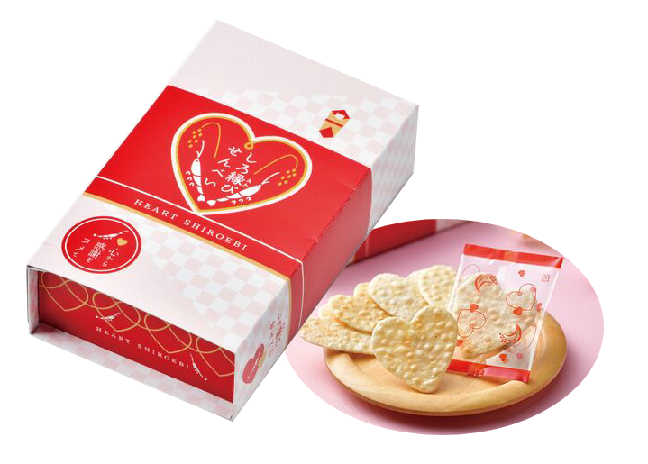 Heart-shaped Japanese glass shrimp rice crackers in red packaging with Toyama rice, lightly salted, on a wooden plate.