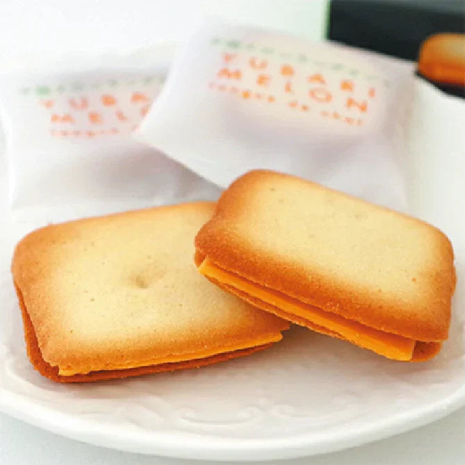 Yubari Melon Langue de Chat cookies on a plate, featuring crispy dough and Yubari melon chocolate filling, packaged elegantly.