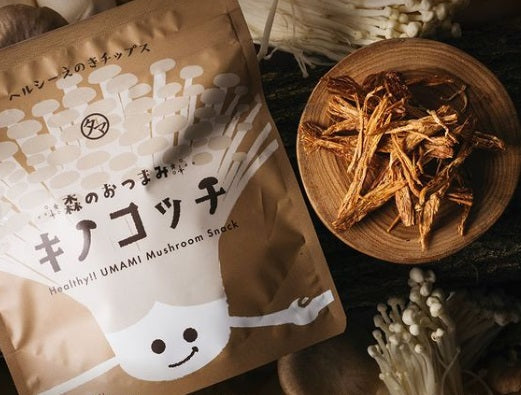 Kinokocchi Mushroom Chips package with shiitake and eringi mushrooms on wooden plate, healthy UMAMI snack rich in dietary fiber.