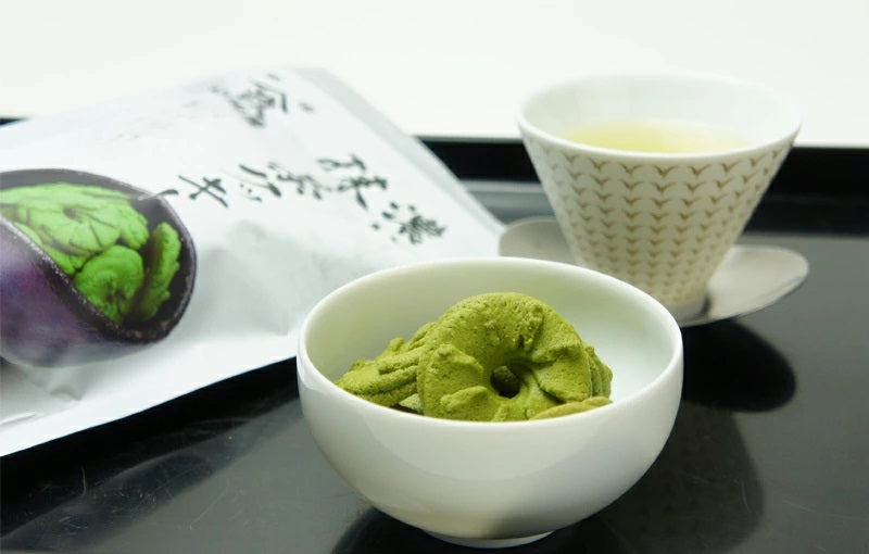 Bowl of rich matcha cookies next to a cup of green tea, showcasing crispy texture and matcha flavor, allergens: wheat, egg, dairy.