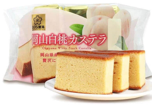 Three slices of moist Okayama White Peach Castella cake in front of packaging, featuring white peach imagery. Contains wheat, egg, dairy, soybean.