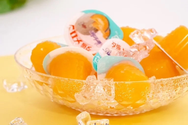 Glass bowl filled with Yubari Melon Jelly Mini pieces on ice, showcasing vibrant orange color; a luxurious treat from Hokkaido.