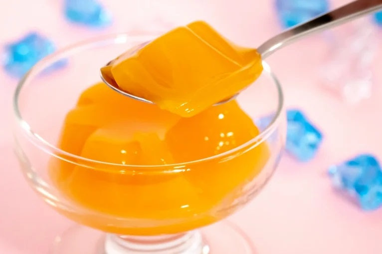 HOKUSHIN FOODS Hokkaido Yubari Melon Jelly in glass dish with spoonful showcasing vibrant orange color and smooth texture.