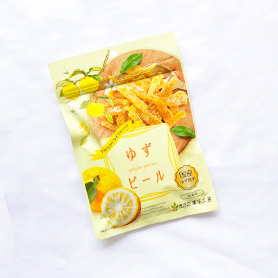 Package of Japanese Yuzu Peel with honey, featuring bite-size slices and vibrant lemon imagery on a white background.