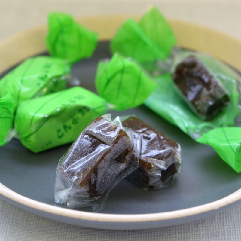 Soft Kelp Candy wrapped in green packaging on a plate, showcasing Hokkaido's flavorful sea kelp treat. Contains wheat and soybean.