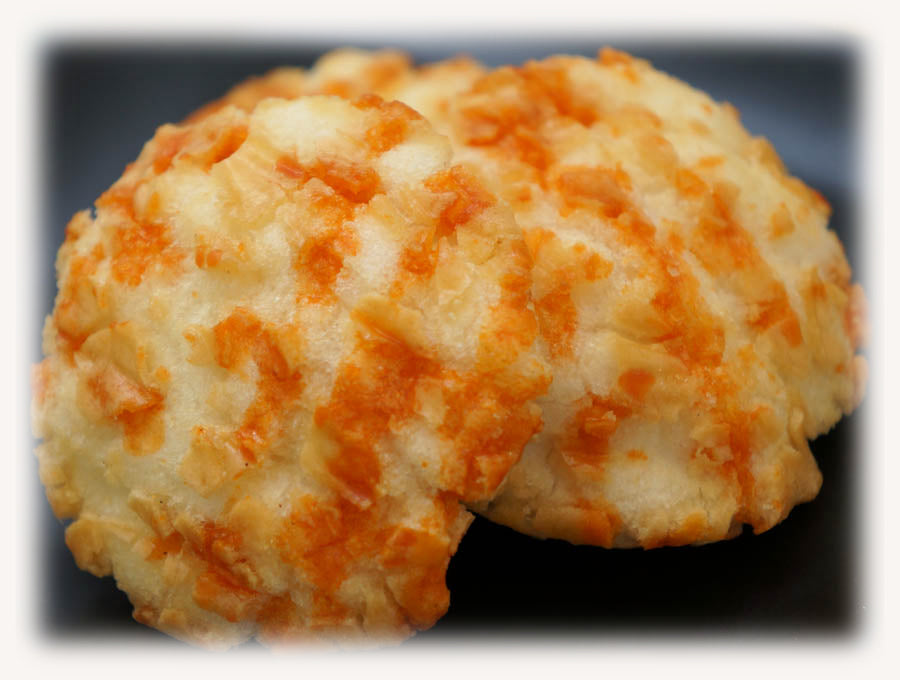 Sea Urchin Rice Crackers with rich sauce, showcasing orange and cream colors on a dark plate. Contains egg, wheat, dairy, squid, soybean.