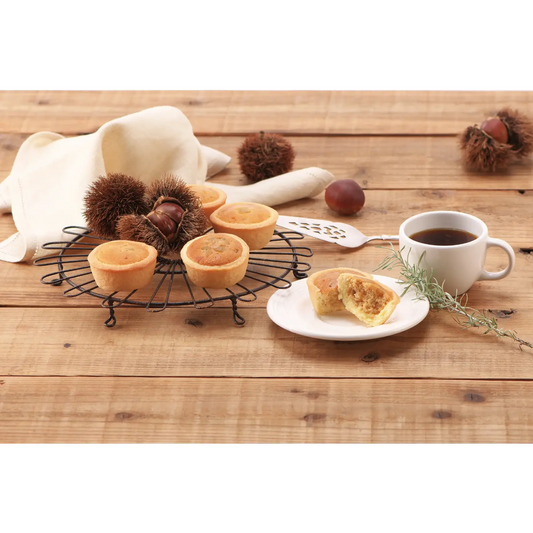 Sweet Marron Tart with chestnuts, caramel, and maple flavors on a wooden table next to a cup of coffee.