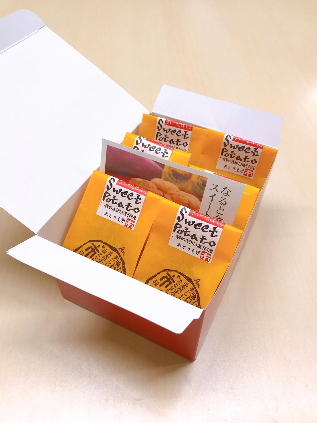 Gift box of Naruto-Kintoki sweet potato cakes from Tokushima, packaged individually in bright yellow wrappers with English and Japanese text.